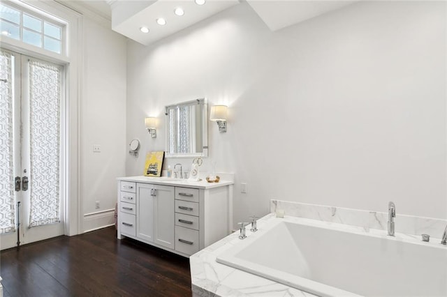 bathroom featuring a relaxing tiled tub, vanity, and hardwood / wood-style floors