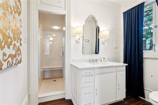 bathroom featuring toilet, hardwood / wood-style flooring, ornamental molding, vanity, and walk in shower