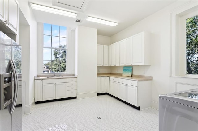 kitchen with white cabinets, washer / clothes dryer, sink, and stainless steel fridge with ice dispenser