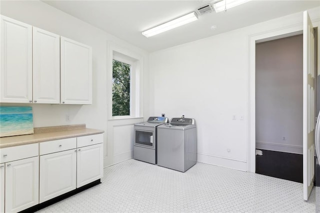 clothes washing area with washing machine and clothes dryer and cabinets