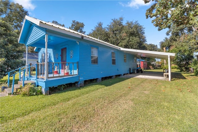 back of house with a porch, a lawn, and a carport