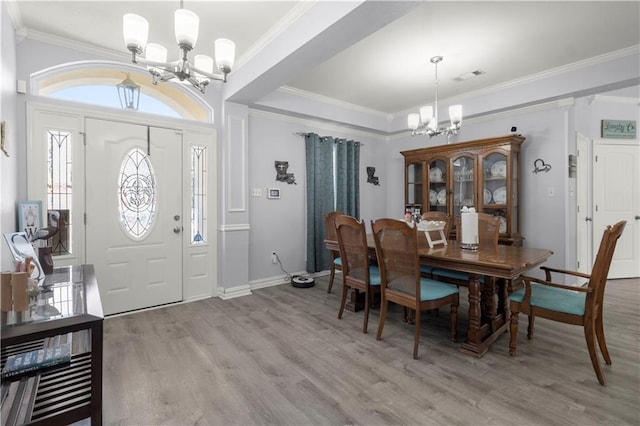 dining space with an inviting chandelier, ornamental molding, and light wood-type flooring