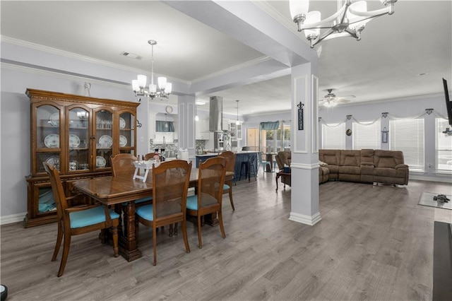 dining space with light hardwood / wood-style floors, crown molding, decorative columns, and ceiling fan with notable chandelier