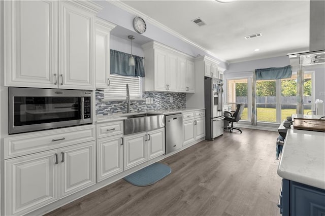 kitchen featuring appliances with stainless steel finishes, white cabinets, hardwood / wood-style flooring, and ornamental molding