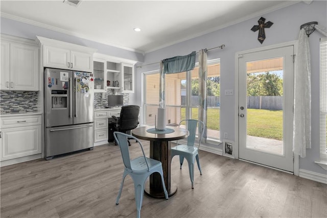 dining space with ornamental molding and light wood-type flooring