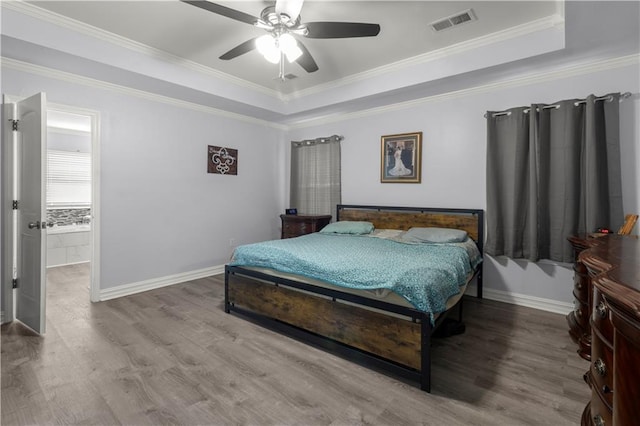 bedroom with ornamental molding, hardwood / wood-style flooring, a raised ceiling, and ceiling fan