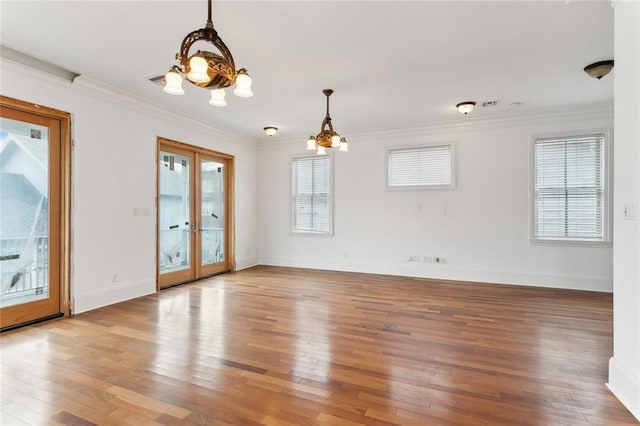 empty room with hardwood / wood-style flooring, ornamental molding, french doors, and a chandelier