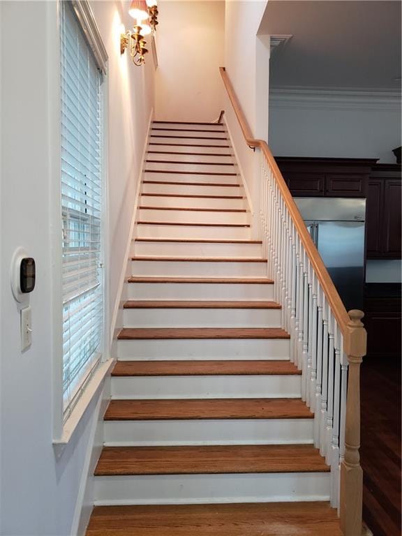 stairway with ornamental molding and hardwood / wood-style flooring