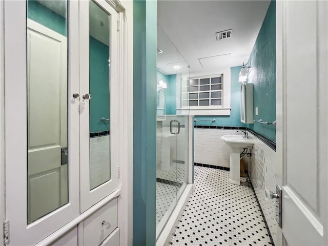 bathroom featuring a shower with shower door and tile walls