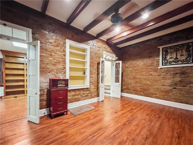 living room with hardwood / wood-style floors, beamed ceiling, and brick wall