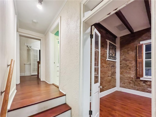 staircase with ornamental molding, hardwood / wood-style flooring, and brick wall