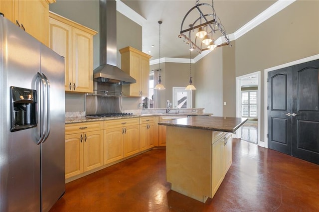 kitchen featuring a center island, wall chimney range hood, backsplash, appliances with stainless steel finishes, and decorative light fixtures