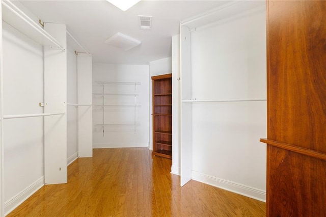 walk in closet with light hardwood / wood-style floors