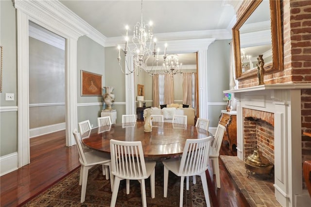 dining space with a fireplace, ornamental molding, an inviting chandelier, and dark hardwood / wood-style floors