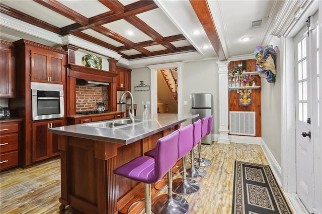 1214 Felicity St, New Orleans, LA 70130 - kitchen with stainless steel countertops, stainless steel appliances, a sink, light wood-type flooring, and beamed ceiling