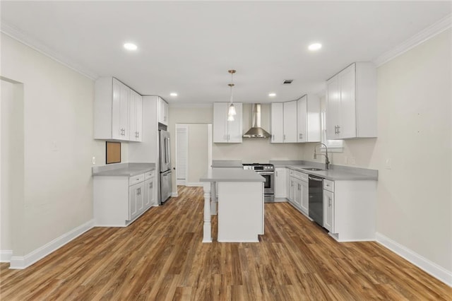 kitchen featuring wall chimney exhaust hood, a kitchen island, appliances with stainless steel finishes, and white cabinetry