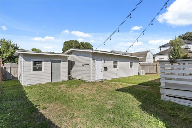 rear view of house featuring central air condition unit, a storage shed, and a yard