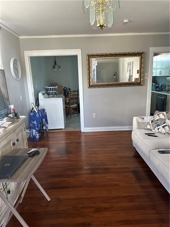 living area with crown molding, separate washer and dryer, baseboards, and wood finished floors