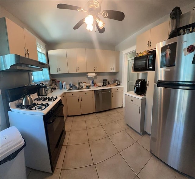 kitchen with a sink, light countertops, light tile patterned floors, under cabinet range hood, and black appliances