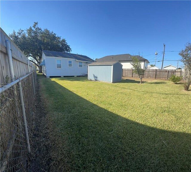 view of yard featuring a storage unit, a fenced backyard, and an outdoor structure