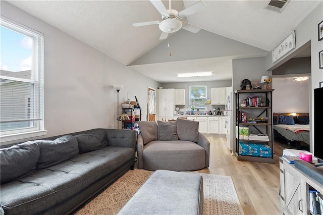 living room with high vaulted ceiling, ceiling fan, light hardwood / wood-style floors, and a wealth of natural light