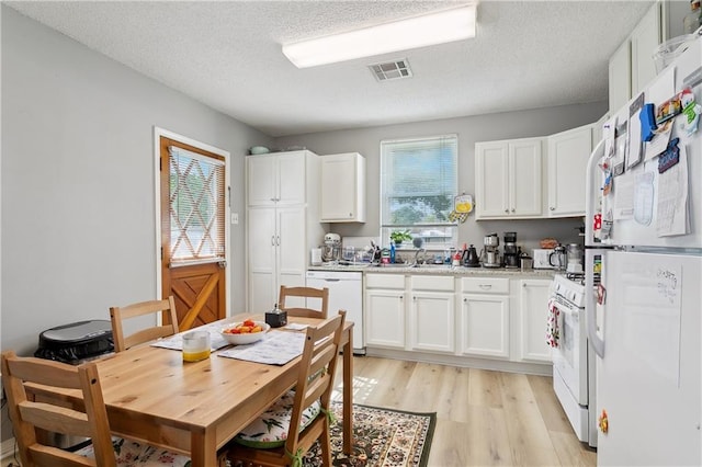 kitchen with a textured ceiling, white cabinets, white appliances, and light wood-type flooring