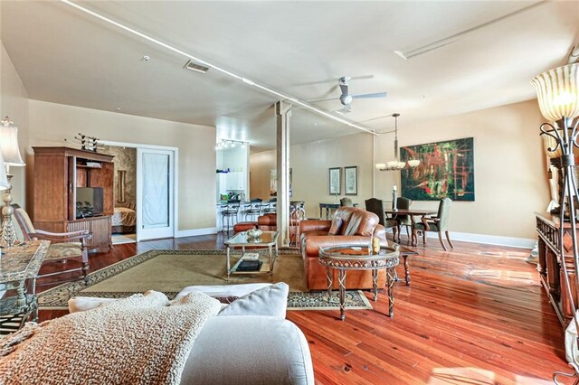 living room with wood-type flooring and ceiling fan with notable chandelier