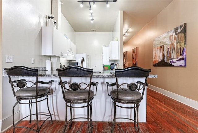 kitchen featuring white cabinetry, kitchen peninsula, dark hardwood / wood-style floors, and white fridge