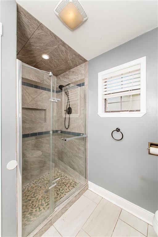 bathroom featuring toilet, tile patterned floors, and an enclosed shower