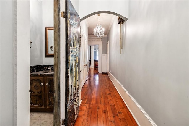 hall featuring an inviting chandelier, crown molding, and hardwood / wood-style flooring