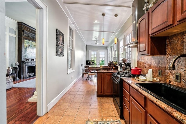 kitchen featuring tasteful backsplash, sink, light tile patterned flooring, decorative light fixtures, and black range with gas cooktop