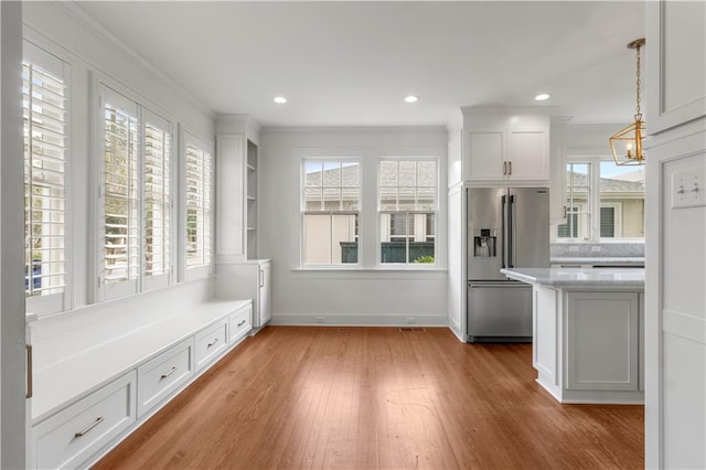 interior space with light wood-type flooring, white cabinetry, high end refrigerator, and plenty of natural light