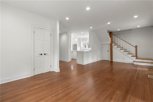 unfurnished living room featuring hardwood / wood-style flooring and crown molding