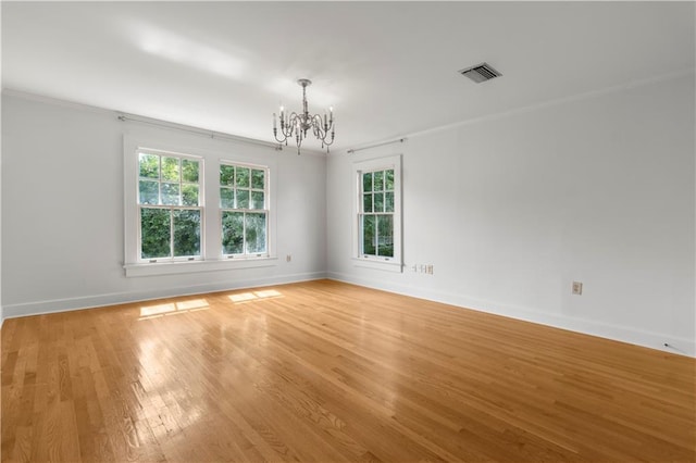 empty room featuring ornamental molding, hardwood / wood-style floors, and a chandelier