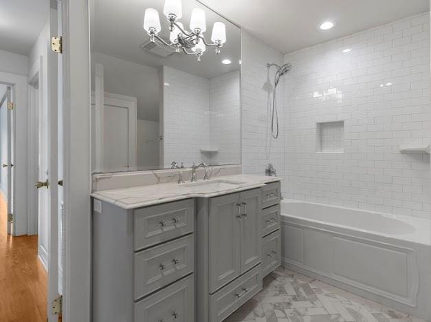 bathroom featuring vanity, hardwood / wood-style flooring, a chandelier, and tiled shower / bath