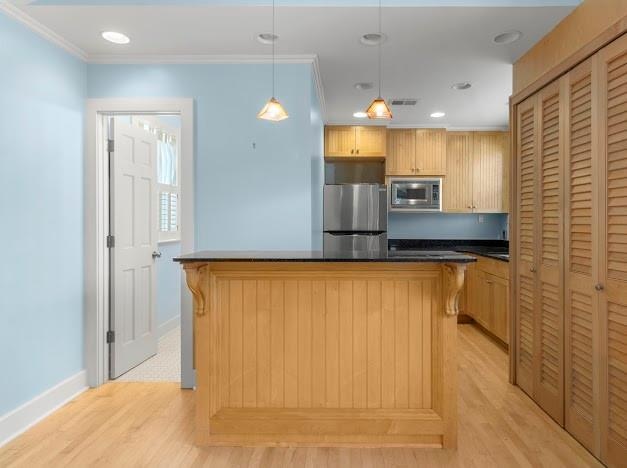 kitchen with stainless steel appliances, ornamental molding, light wood-type flooring, a center island, and pendant lighting