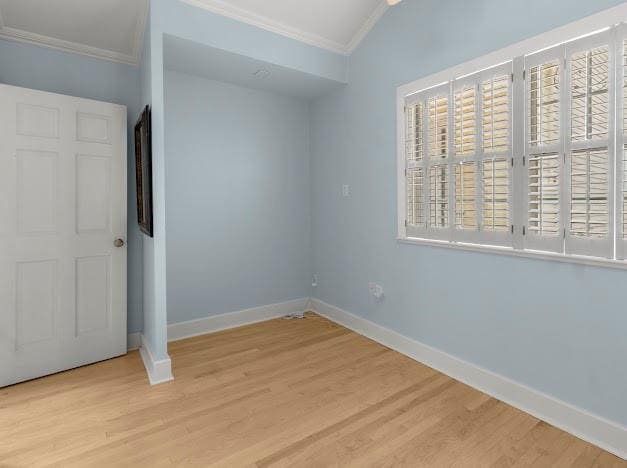 unfurnished bedroom featuring lofted ceiling, light hardwood / wood-style flooring, and crown molding