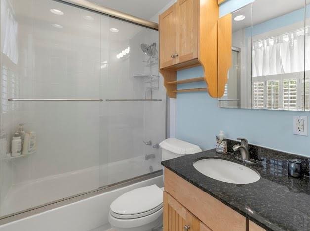 full bathroom with toilet, vanity, and shower / bath combination with glass door