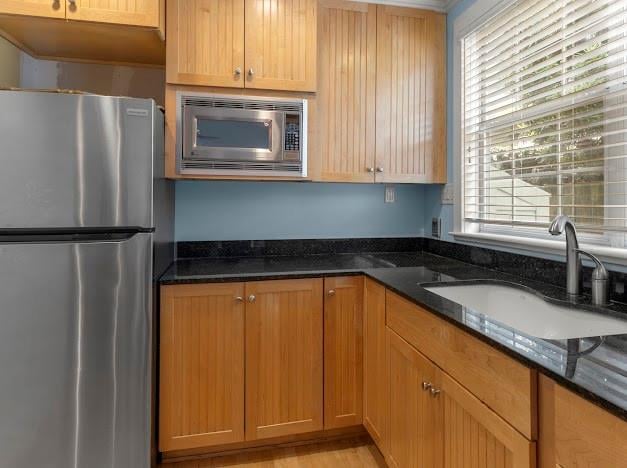 kitchen featuring stainless steel appliances, dark stone countertops, and sink