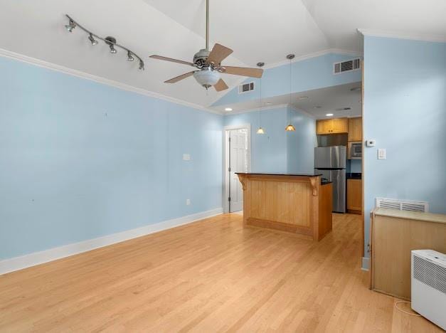 kitchen with decorative light fixtures, light hardwood / wood-style flooring, crown molding, lofted ceiling, and stainless steel fridge