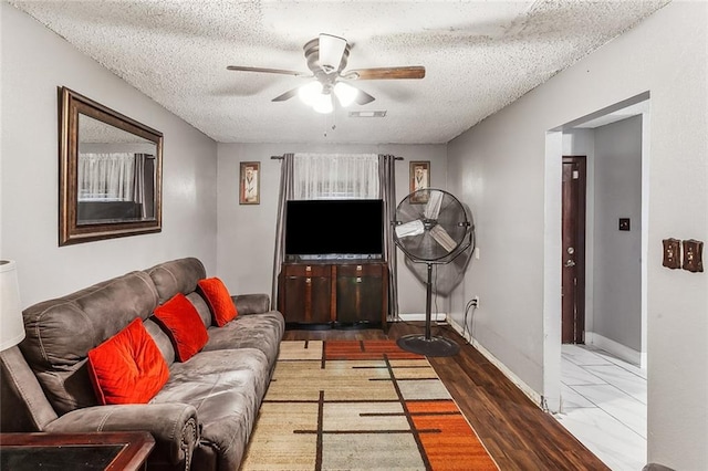 living room featuring a textured ceiling, dark wood-type flooring, and ceiling fan