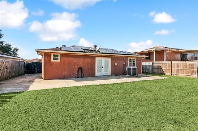 back of house with french doors, a patio, a yard, and solar panels