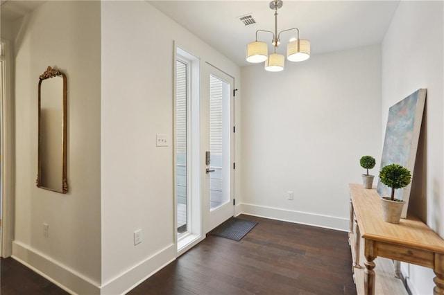 foyer entrance featuring dark hardwood / wood-style floors and a notable chandelier