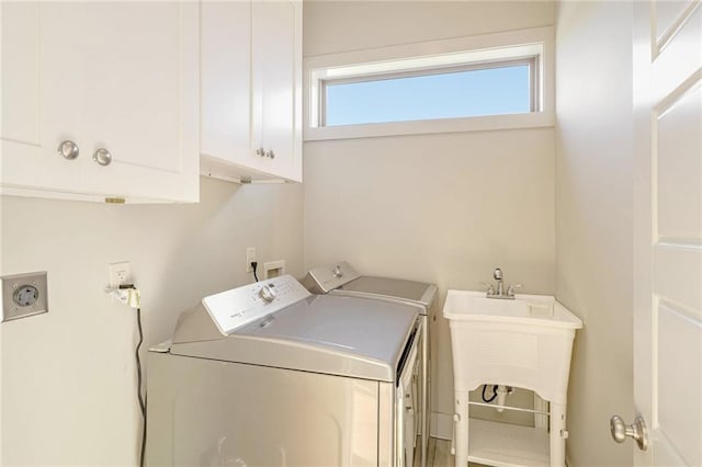 clothes washing area with cabinets, washing machine and clothes dryer, and sink