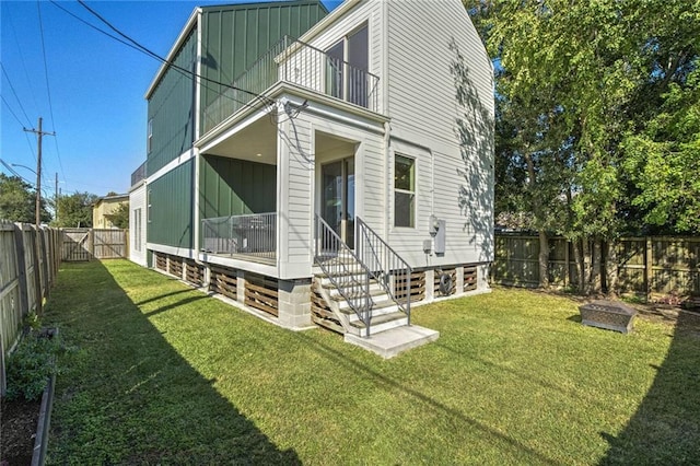 back of property featuring a balcony and a lawn