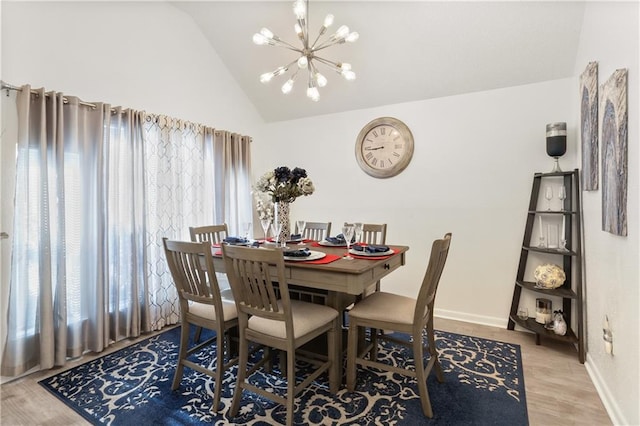 dining space featuring an inviting chandelier, hardwood / wood-style floors, vaulted ceiling, and a healthy amount of sunlight