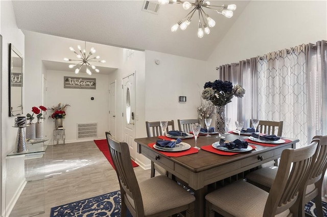 dining room featuring a notable chandelier, hardwood / wood-style flooring, plenty of natural light, and vaulted ceiling