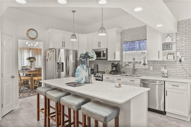 kitchen featuring a center island, white cabinetry, decorative light fixtures, and stainless steel appliances