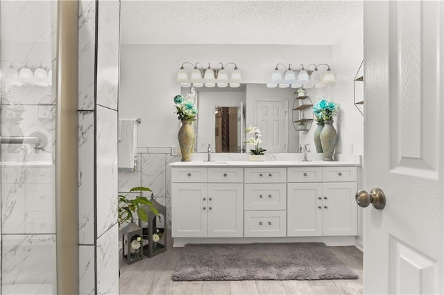 bathroom featuring vanity, a textured ceiling, wood-type flooring, and tile walls