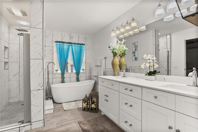 bathroom with plus walk in shower, wood-type flooring, vanity, tile walls, and a textured ceiling